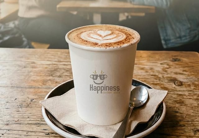Latte with heart art in a Happiness Corner Cafe takeaway cup
